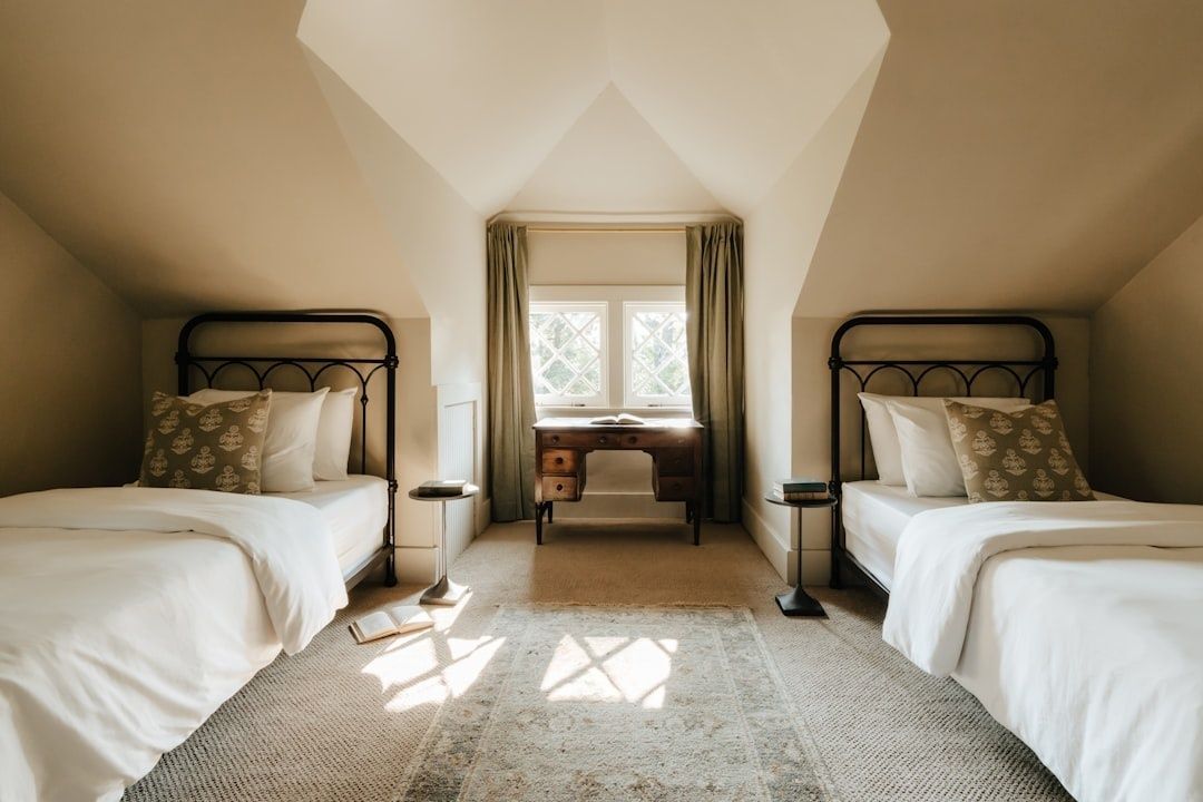 Chambre mansardée avec deux lits, baignée par la lumière d’une fenêtre
