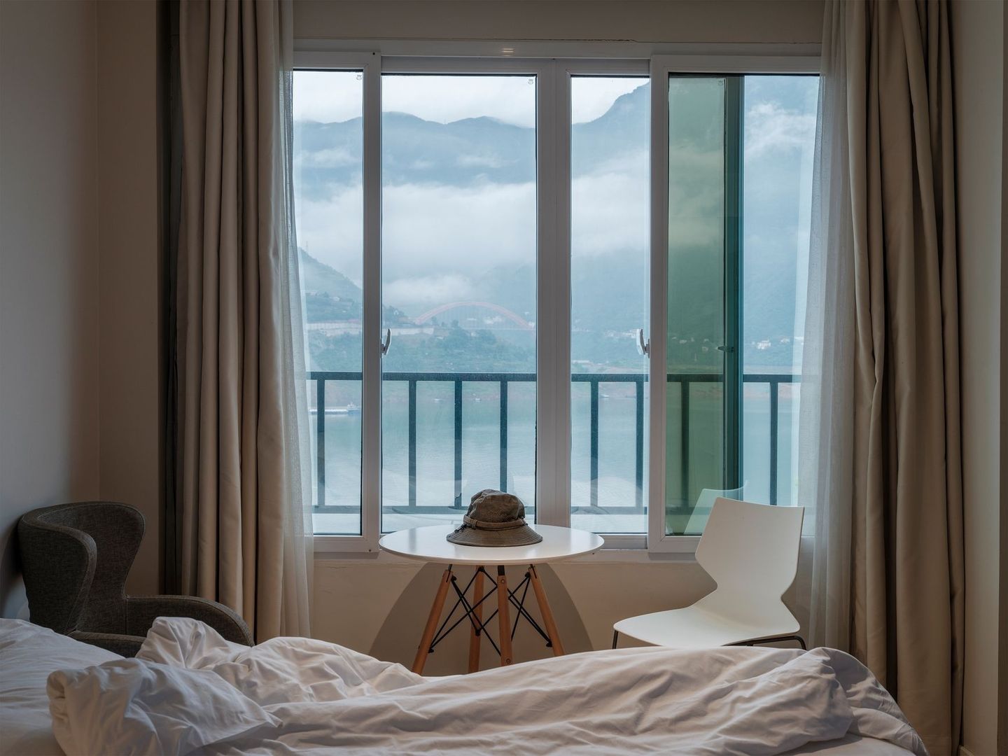 Chambre avec fenêtre panoramique donnant sur un lac et des montagnes