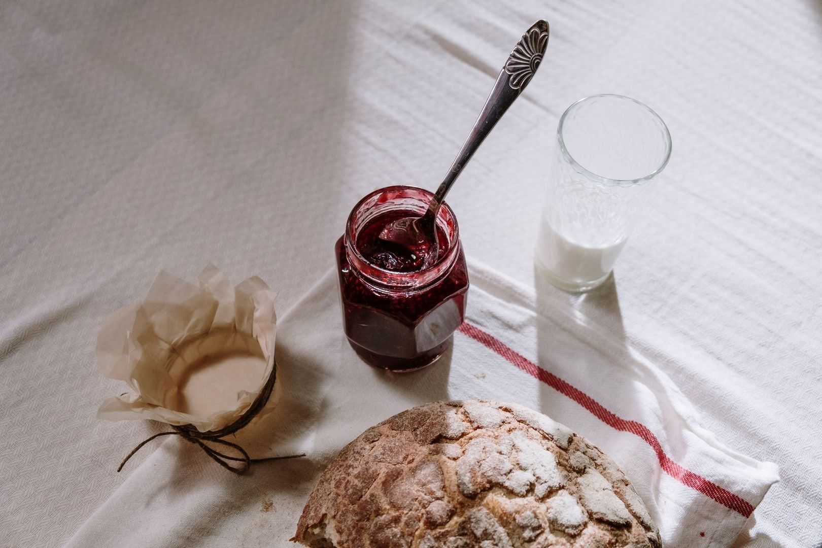 Pain artisanal, confiture maison et verre de lait sur une table